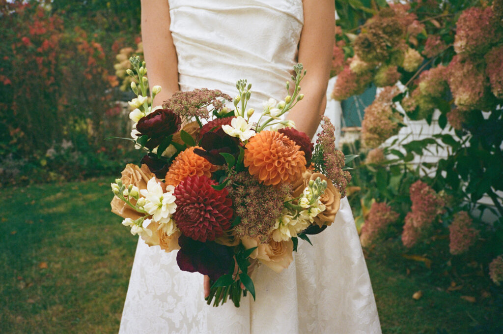 A fall bridal bouquet featuring dahlias, chocolate queen anne's lace, and burgundy ranunculus.