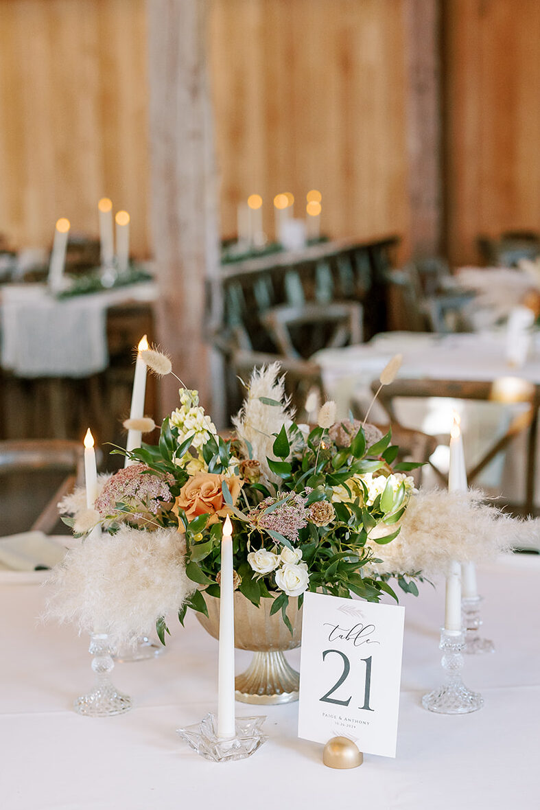 A centerpiece in a gold compote with beautiful fall colors, and fluffy pampas grasses.