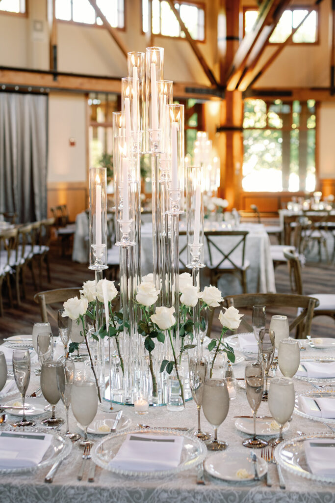 Round table shown with bud vases featuring a white single stem rose, and a candelabra.