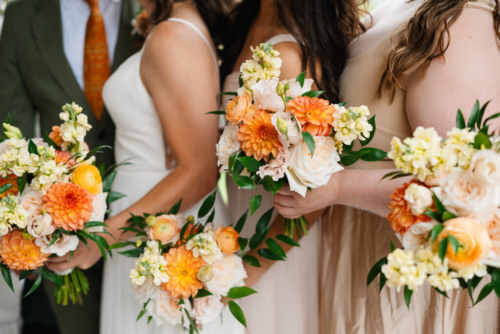 The groom, bride and brides maid standing with their bouquets featured. 