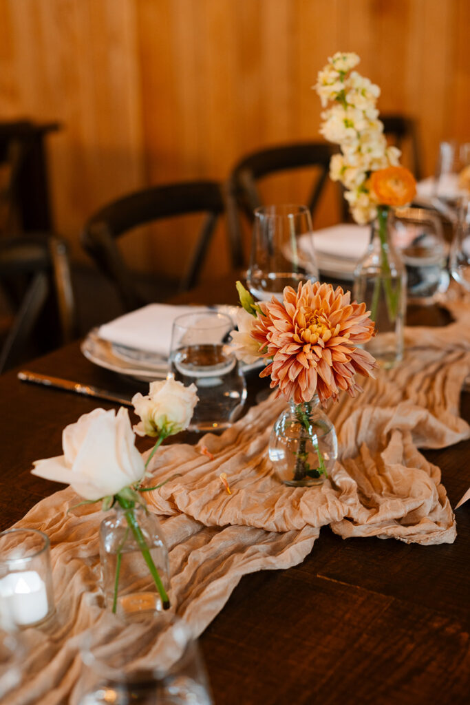 Farmhouse table decorated with bud vases, and a linen runner. 