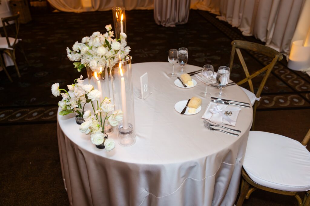 The couples' sweetheart table with pin-frog floral arrangements featuring white sweet peas and ranunculus.
